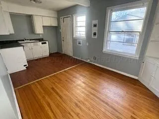 a kitchen with stainless steel appliances a stove a refrigerator a sink and white cabinets with wooden floor