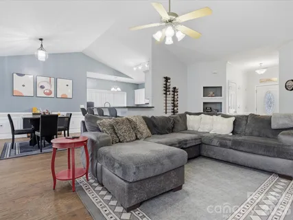 a living room with furniture a clock on wall and a chandelier