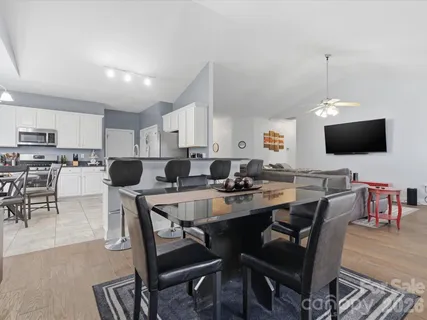 a kitchen with a dining table chairs and a view of living room