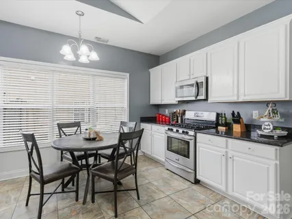 a kitchen with stainless steel appliances granite countertop a white table and chairs
