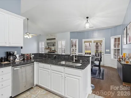 a kitchen with granite countertop a sink a stove and cabinets