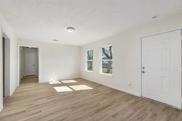 an empty room with wooden floor and windows