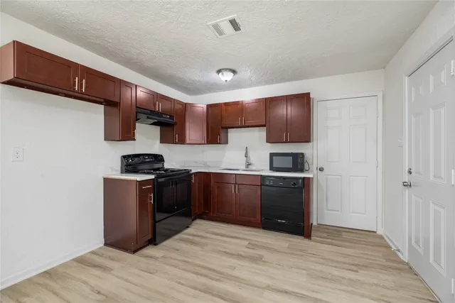 a kitchen with granite countertop a refrigerator stove top oven and sink