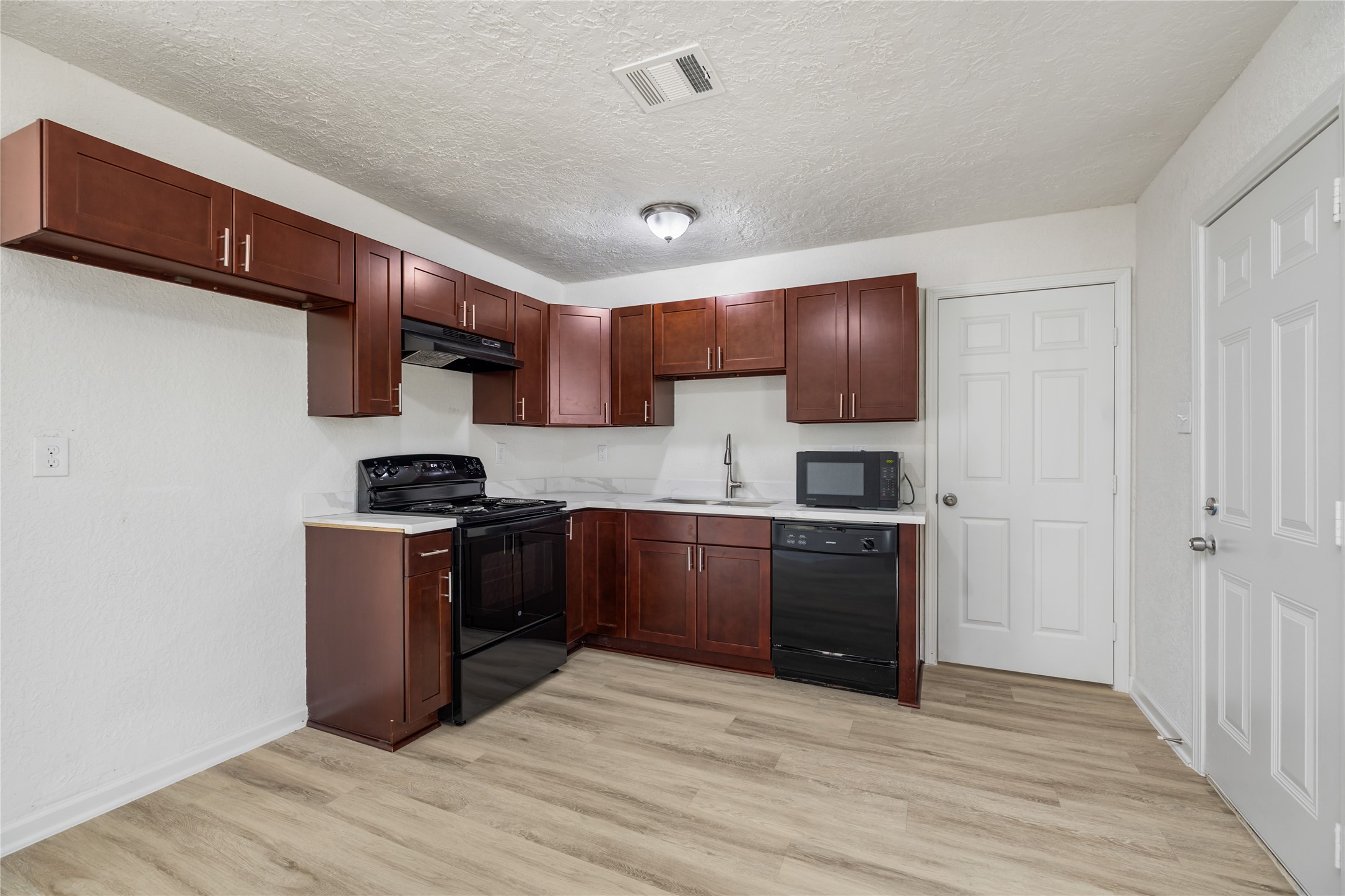 5915 Beldart Street Houston, TX 77033 - Photo 3 of 15 a kitchen with granite countertop a refrigerator stove top oven and sink