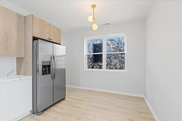 a view of a refrigerator in kitchen and an empty room