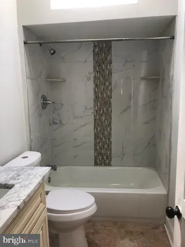 a bathroom with a granite countertop sink a toilet and a mirror