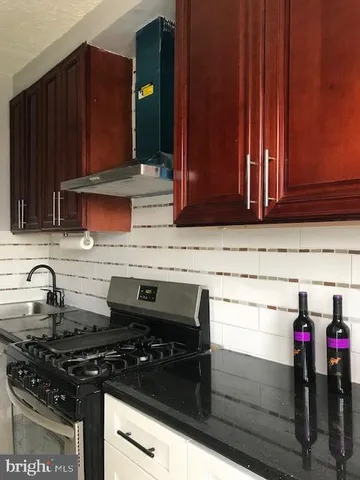 a kitchen with granite countertop a sink stove and cabinets