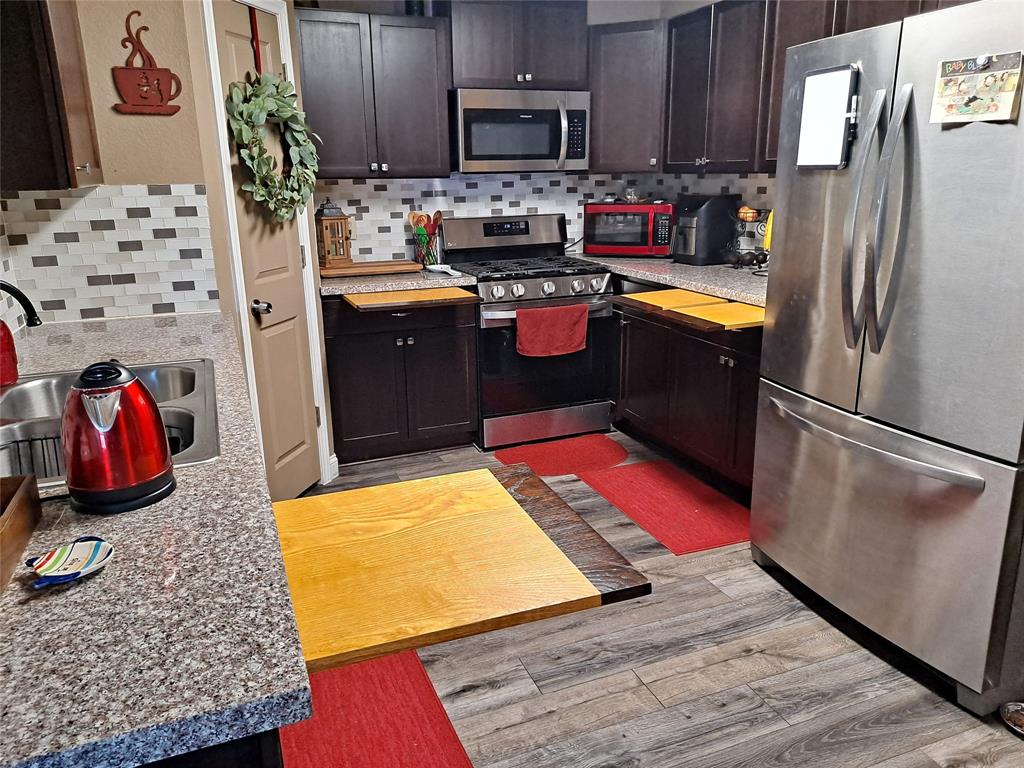 2877 Fenwick Street Grand Prairie, TX 75052 - Photo 11 of 27 a kitchen with stainless steel appliances granite countertop a refrigerator stove and wooden cabinets