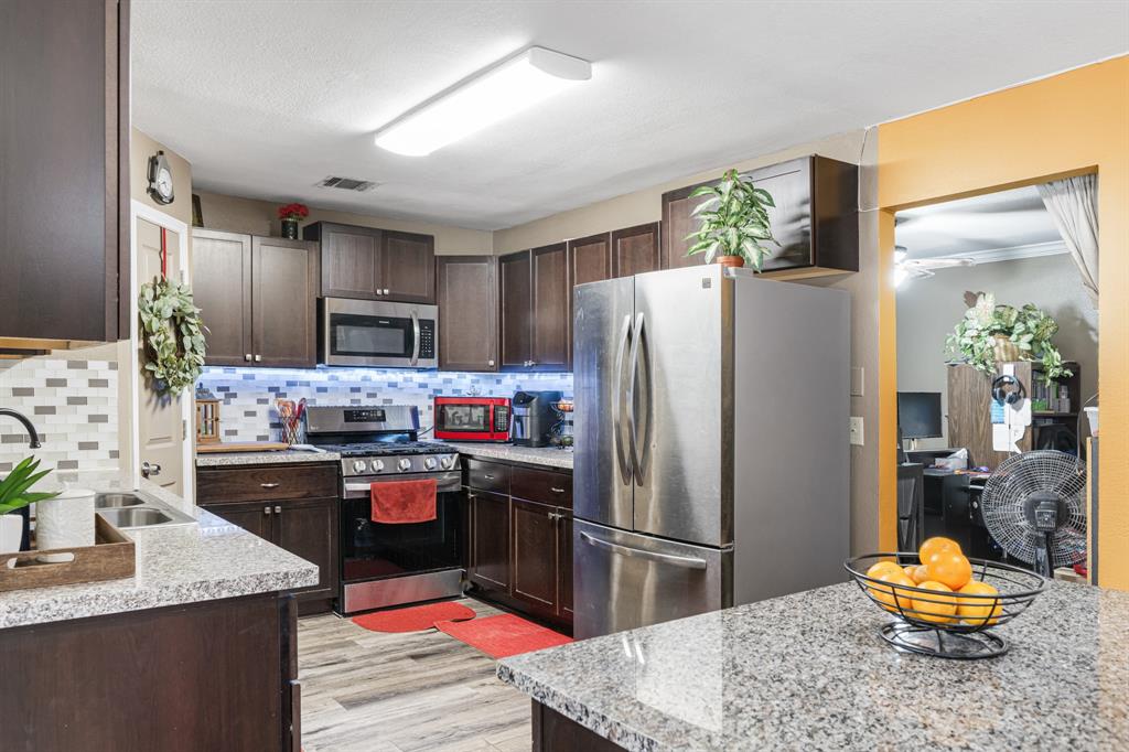 2877 Fenwick Street Grand Prairie, TX 75052 - Photo 7 of 27 a kitchen with kitchen island a refrigerator stove and sink