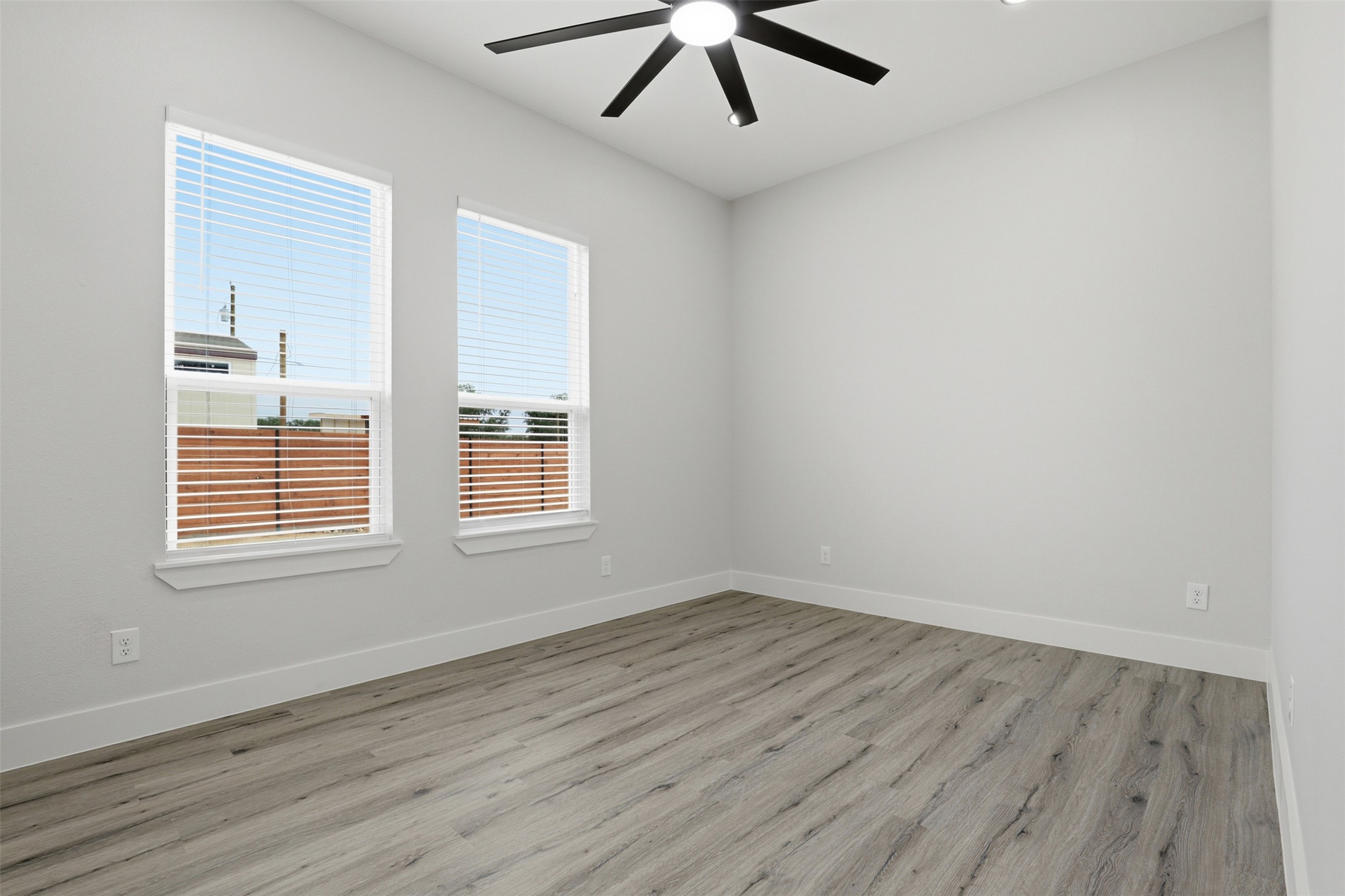 113 Los Robles Road Elgin, TX 78621 - Photo 14 of 20 Spacious room featuring two large windows with blinds, wood-finish flooring, a ceiling fan with integrated lighting, and recessed ceiling lights