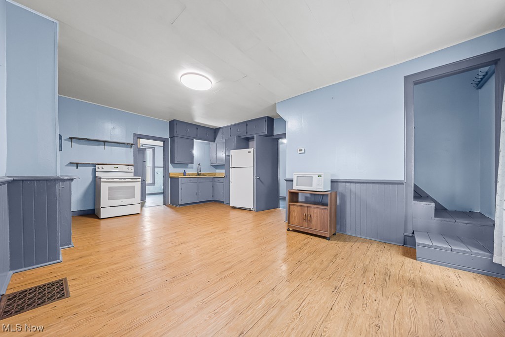 1425 Killian Road Akron, OH 44312 - Photo 3 of 41 Kitchen featuring light wood finished floors, white appliances, blue cabinets, a wainscoted wall, and light countertops