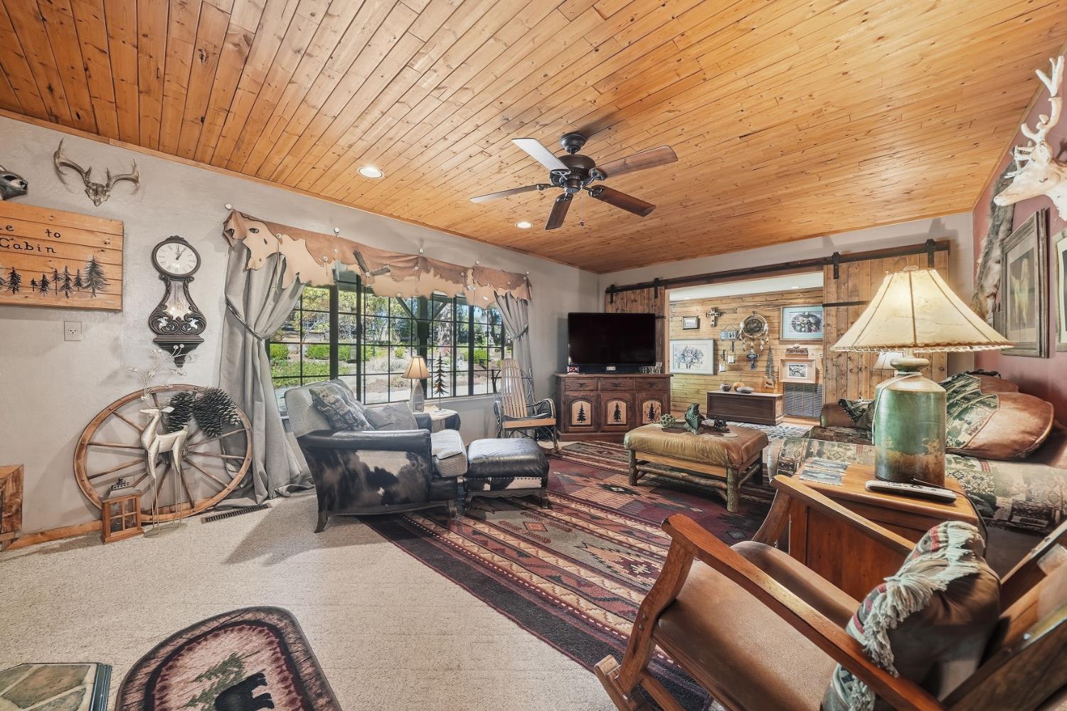 23140 Shake Ridge Road Volcano, CA 95689 - Photo 16 of 81 a living room with furniture ceiling fan and a floor to ceiling window