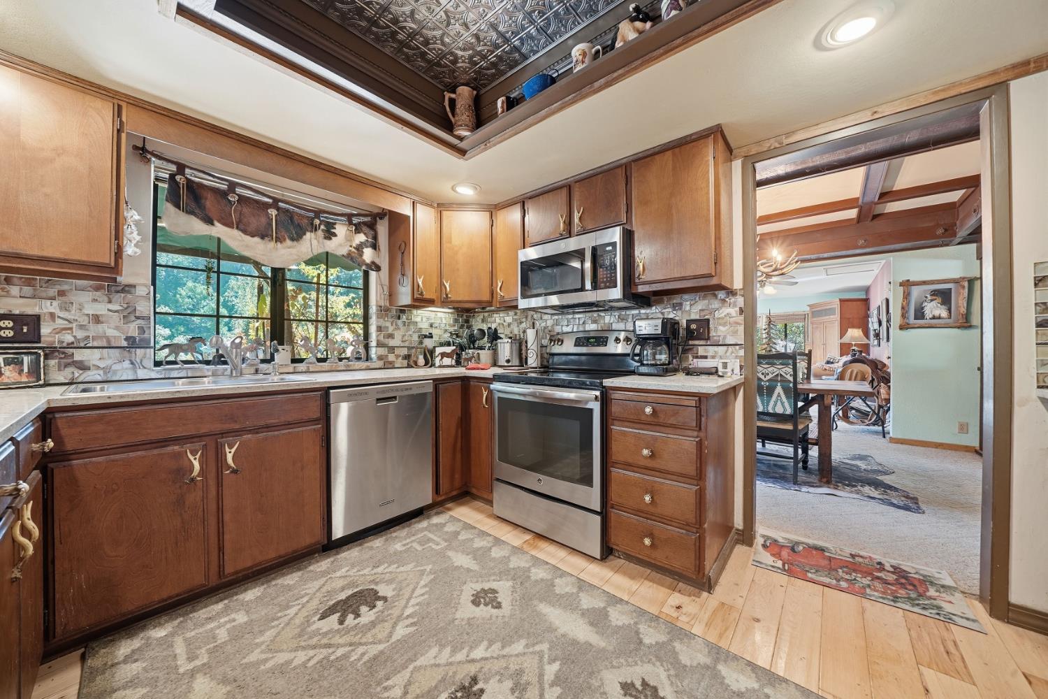 23140 Shake Ridge Road Volcano, CA 95689 - Photo 29 of 81 a kitchen with stainless steel appliances granite countertop a stove top oven a sink dishwasher a dining table and chairs with wooden floor