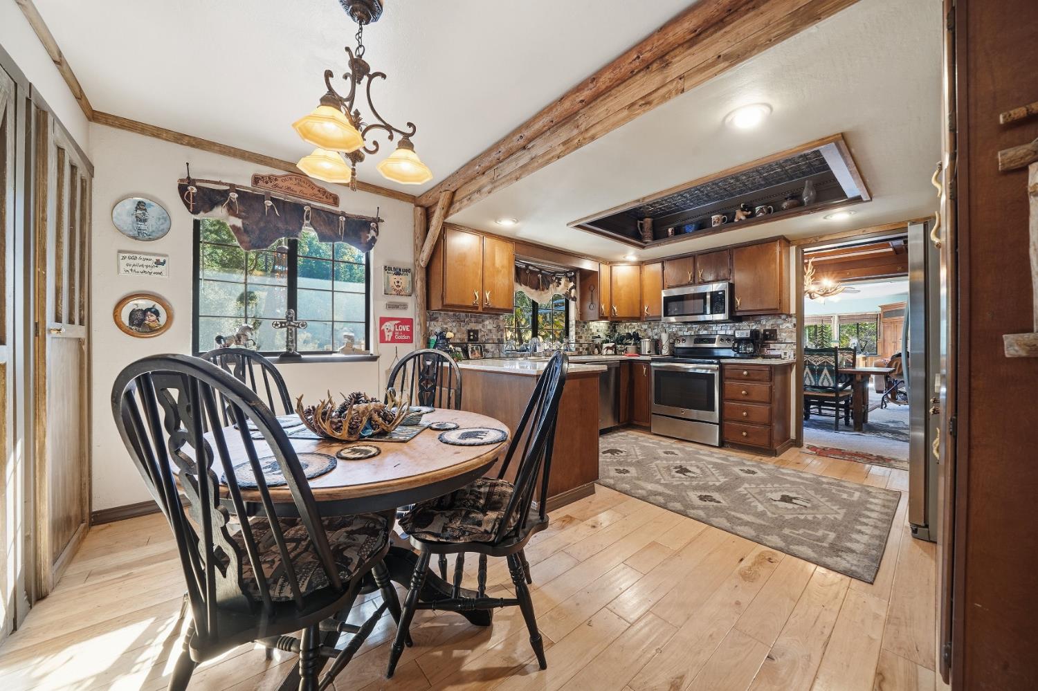 23140 Shake Ridge Road Volcano, CA 95689 - Photo 33 of 81 a dining room with wooden floor a chandelier a wooden table and chairs