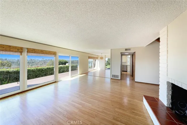 a view of empty room with wooden floor and fireplace