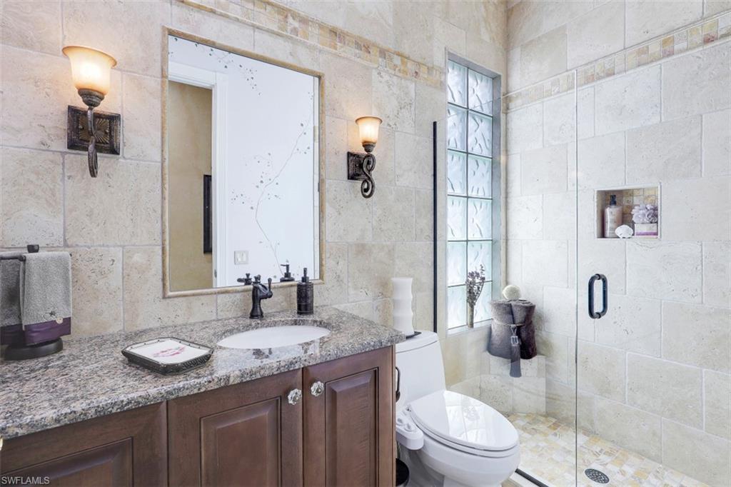 5156 Inagua Way Naples, FL 34119 - Photo 22 of 35 Totally re-imagined Bathroom now has Walk-in Shower, upgraded Cabinets with Granite counters and Travertine Wall and Floor finishes