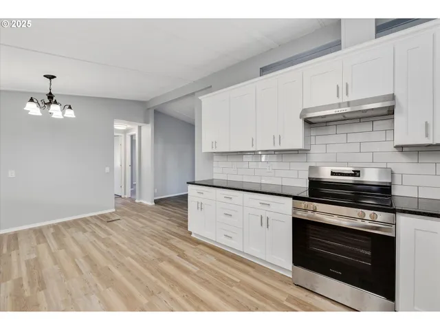 a kitchen with granite countertop a stove cabinets and wooden floor