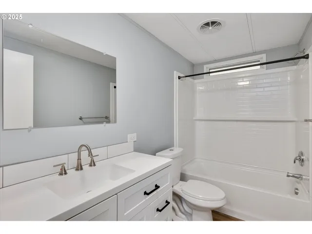 a bathroom with a double vanity sink toilet mirror and shower