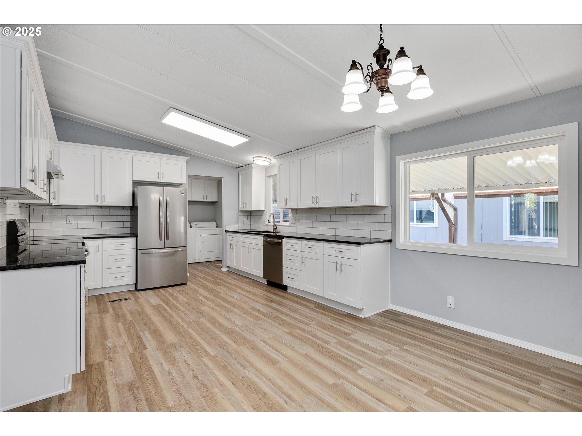 835 Southeast 1st Avenue, Unit 17 Canby, OR 97013 - Photo 9 of 33 a kitchen with stainless steel appliances granite countertop a refrigerator a stove a sink dishwasher and white cabinets with wooden floor