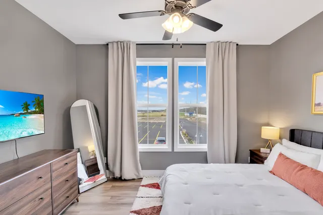 a bedroom with a bed a flat screen tv and a large window