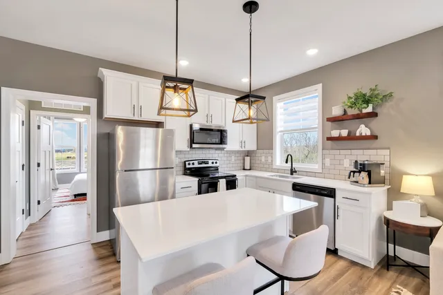 a kitchen with stainless steel appliances a dining table chairs refrigerator and microwave