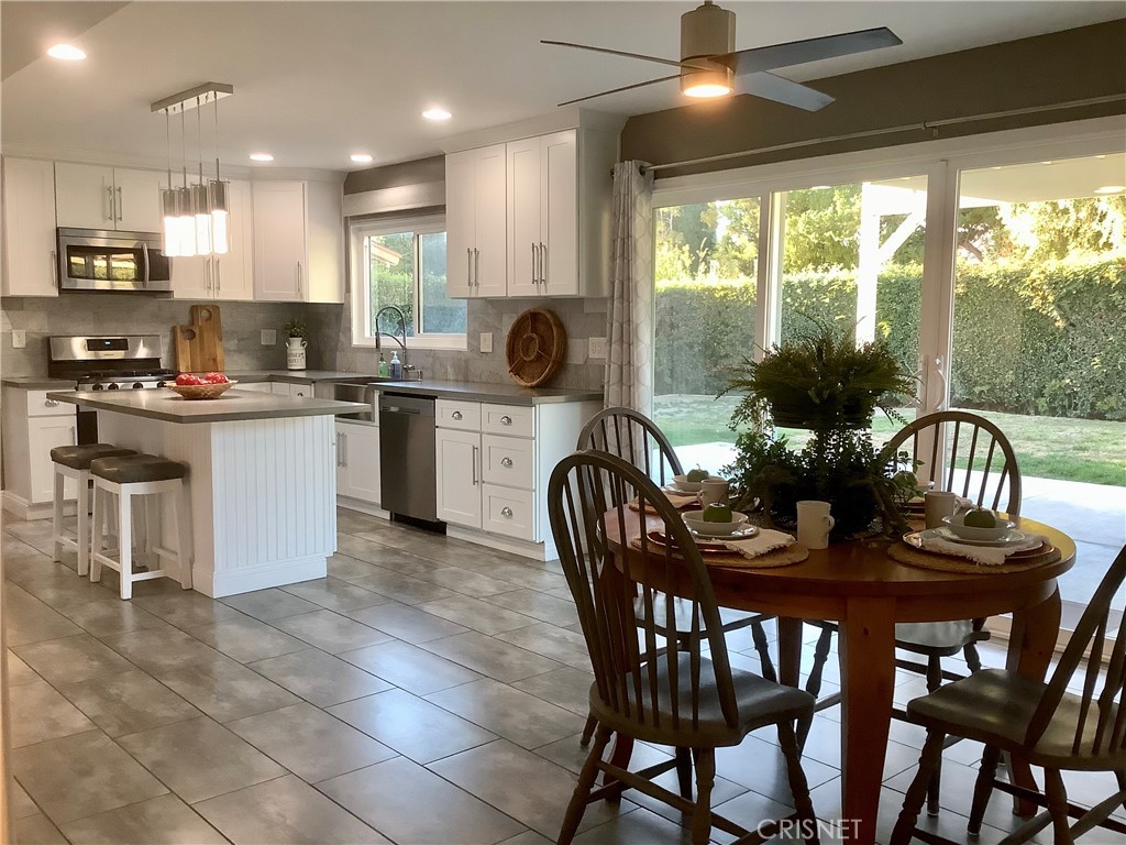 2163 Cheam Avenue Simi Valley, CA 93063 - Photo 4 of 43 a kitchen with stainless steel appliances granite countertop a stove a refrigerator a kitchen island a table and chairs with wooden floor