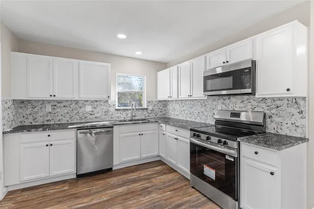 a kitchen with granite countertop a stove top oven sink and cabinets
