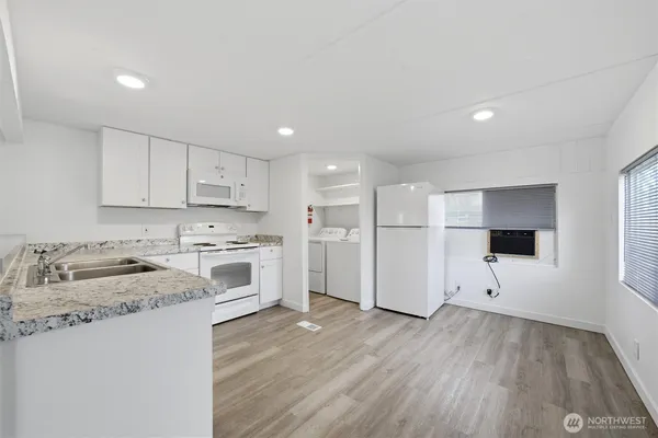 a kitchen with granite countertop white cabinets and white appliances