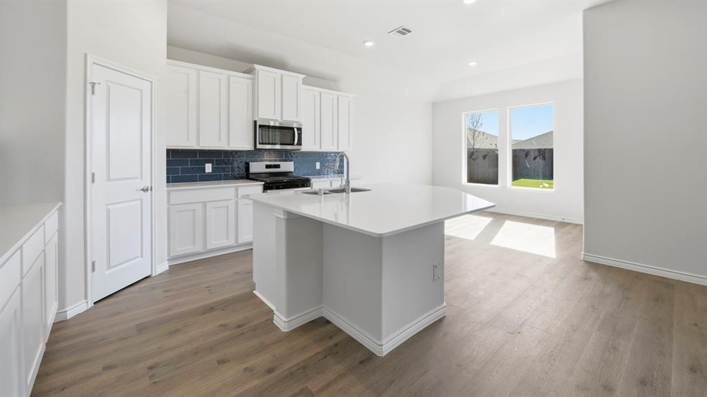 2104 Eugene Street Anna, TX 75409 - Photo 20 of 37 a kitchen with stainless steel appliances granite countertop a stove top oven a sink and a granite counter tops with wooden floors