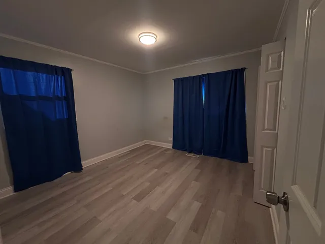an empty room with wooden floor & closet area