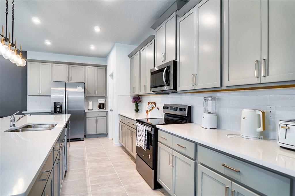 2341 Salty Winds Way Kissimmee, FL 34747 - Photo 13 of 79 a kitchen with stainless steel appliances granite countertop a sink stove refrigerator and cabinets