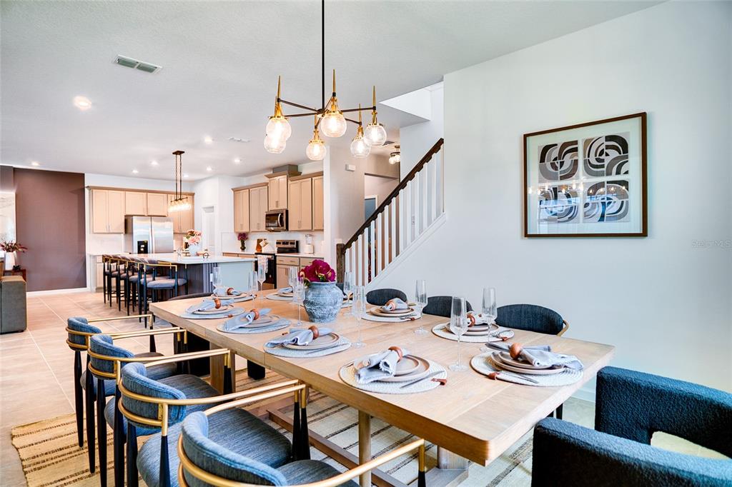 2341 Salty Winds Way Kissimmee, FL 34747 - Photo 17 of 79 a dining room with stainless steel appliances kitchen island granite countertop a dining table chairs and a refrigerator