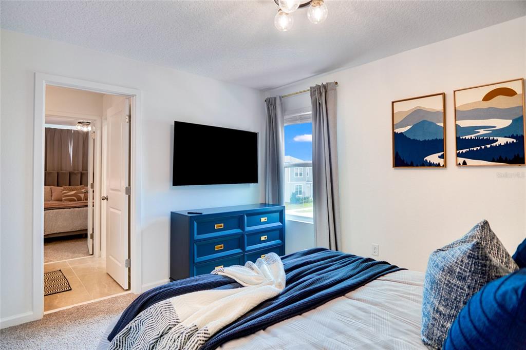 2341 Salty Winds Way Kissimmee, FL 34747 - Photo 63 of 79 a bedroom with a bed and a flat tv screen on a dresser