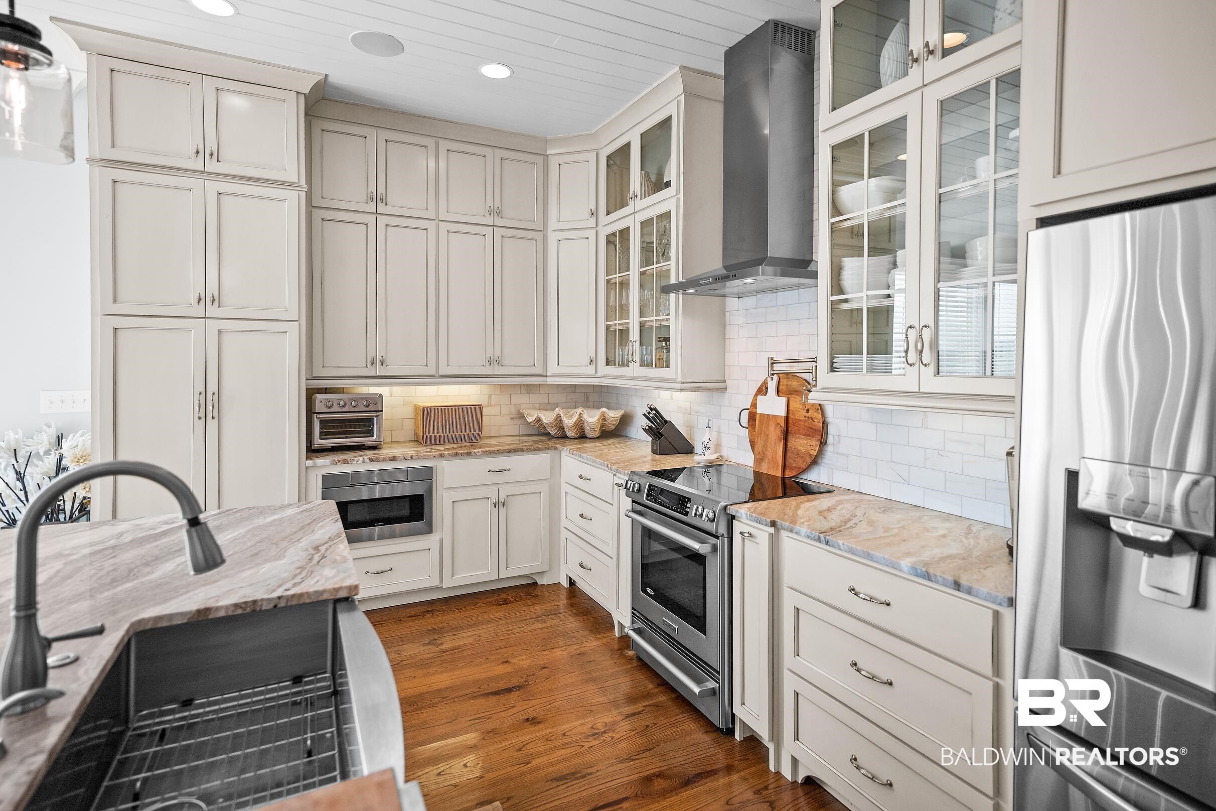 33186 Marlin Key Drive Orange Beach, AL 36561 - Photo 36 of 87 Kitchen featuring stainless steel appliances, light stone countertops, dark wood-type flooring, decorative backsplash, and glass insert cabinets