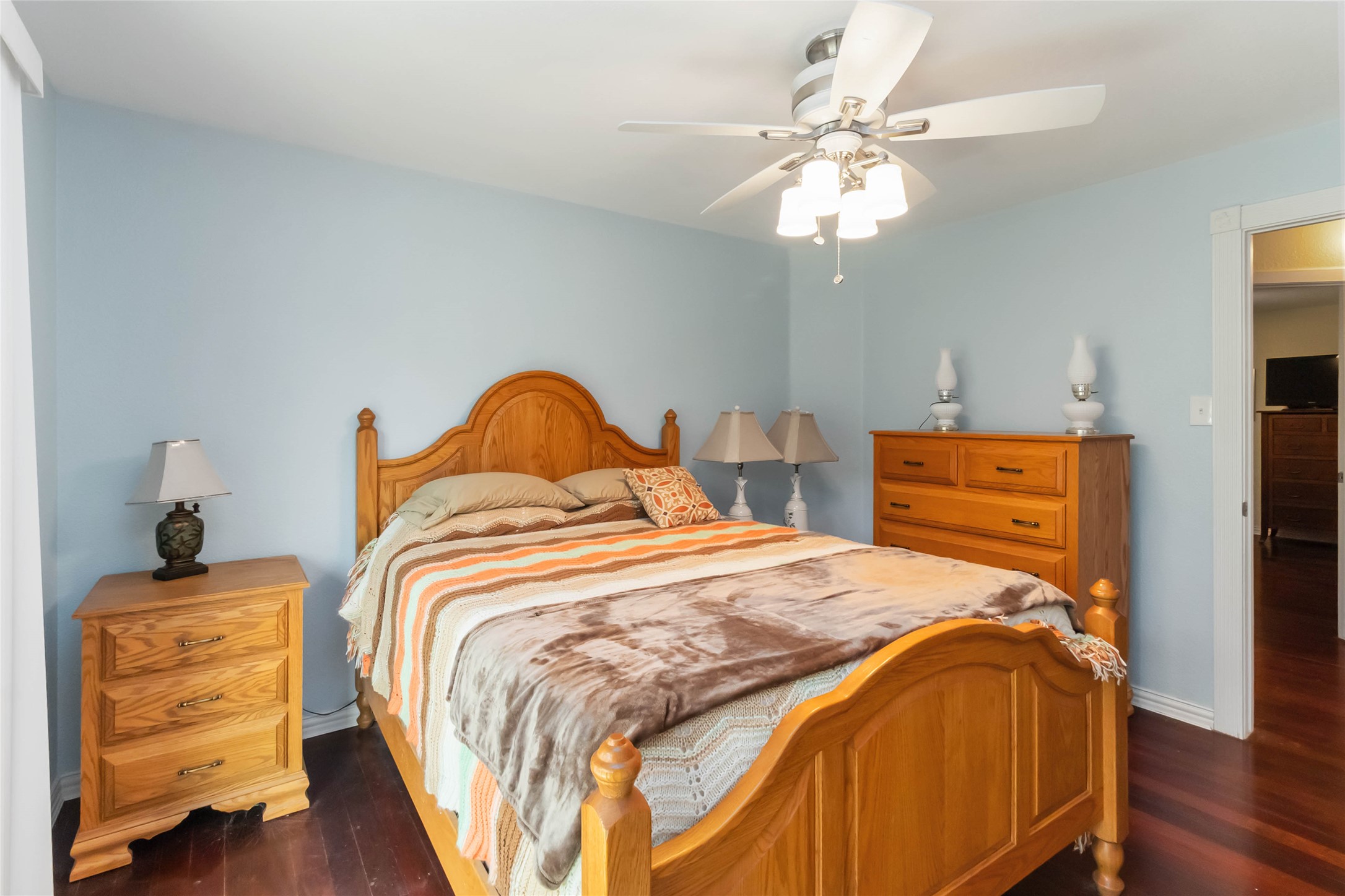 1208 Jeddo Road Rosanky, TX 78953 - Photo 21 of 40 A well-lit bedroom featuring rich hardwood flooring and a functional ceiling fan with lighting.