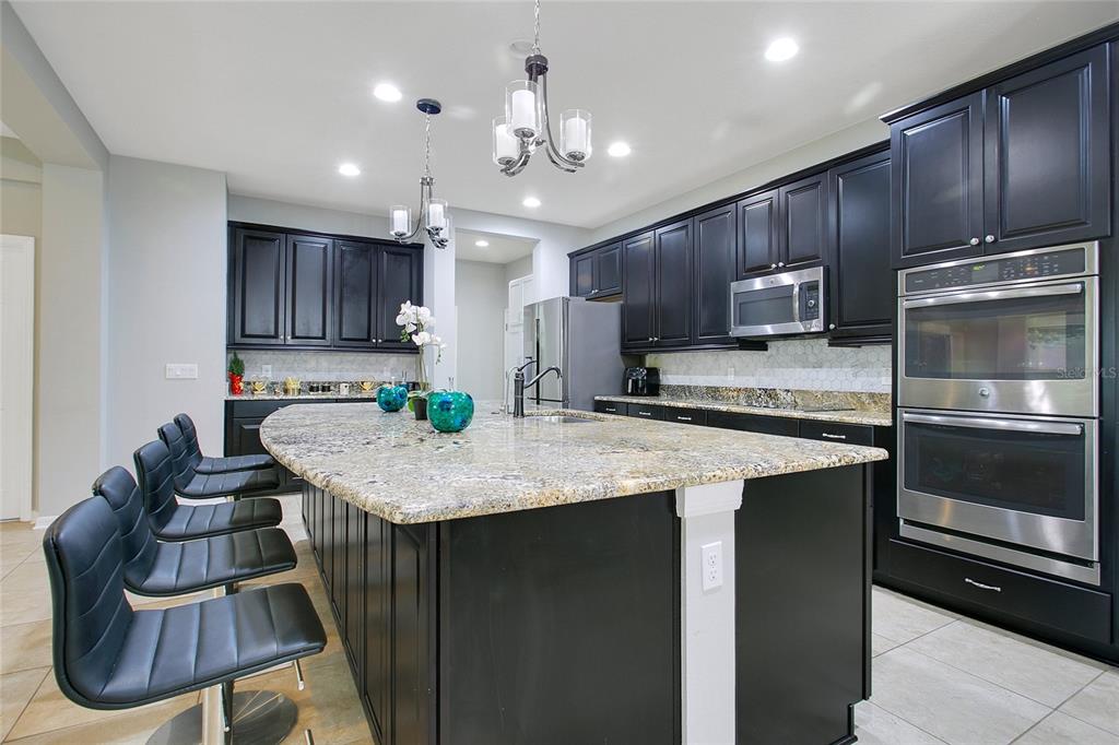 4918 Wildwood Pointe Road Winter Garden, FL 34787 - Photo 8 of 33 a kitchen with kitchen island granite countertop wooden cabinets and a refrigerator