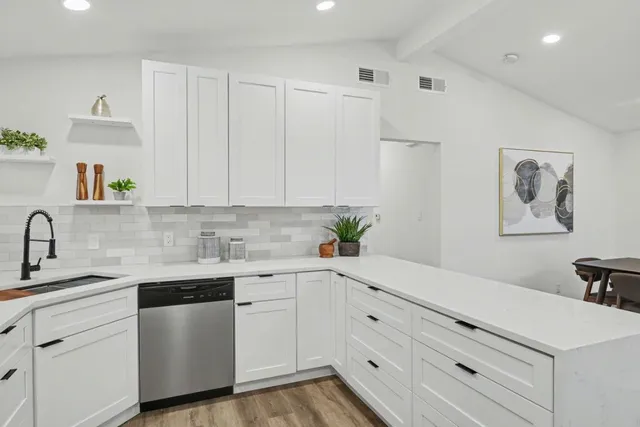 a kitchen with white cabinets and sink