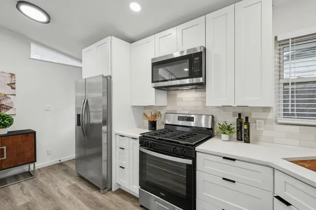a kitchen with stainless steel appliances white cabinets and a stove top oven