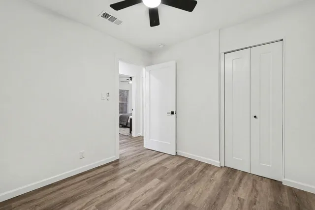 a view of an empty room with window and wooden floor