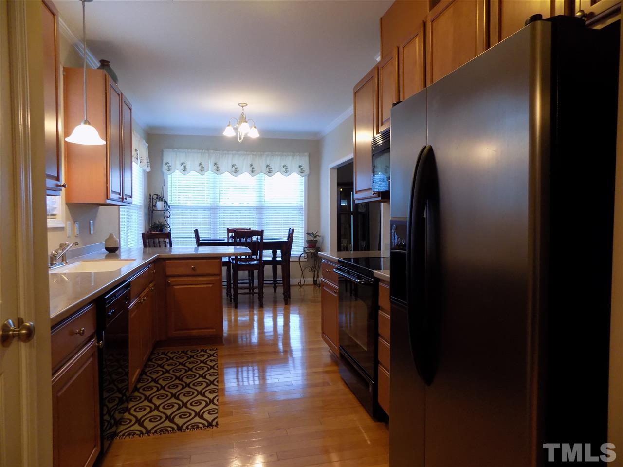 3914 Magnolia Pond Road Raleigh, NC 27610 - Photo 5 of 15 a dining hall with stainless steel appliances a dining table and chairs with wooden floor