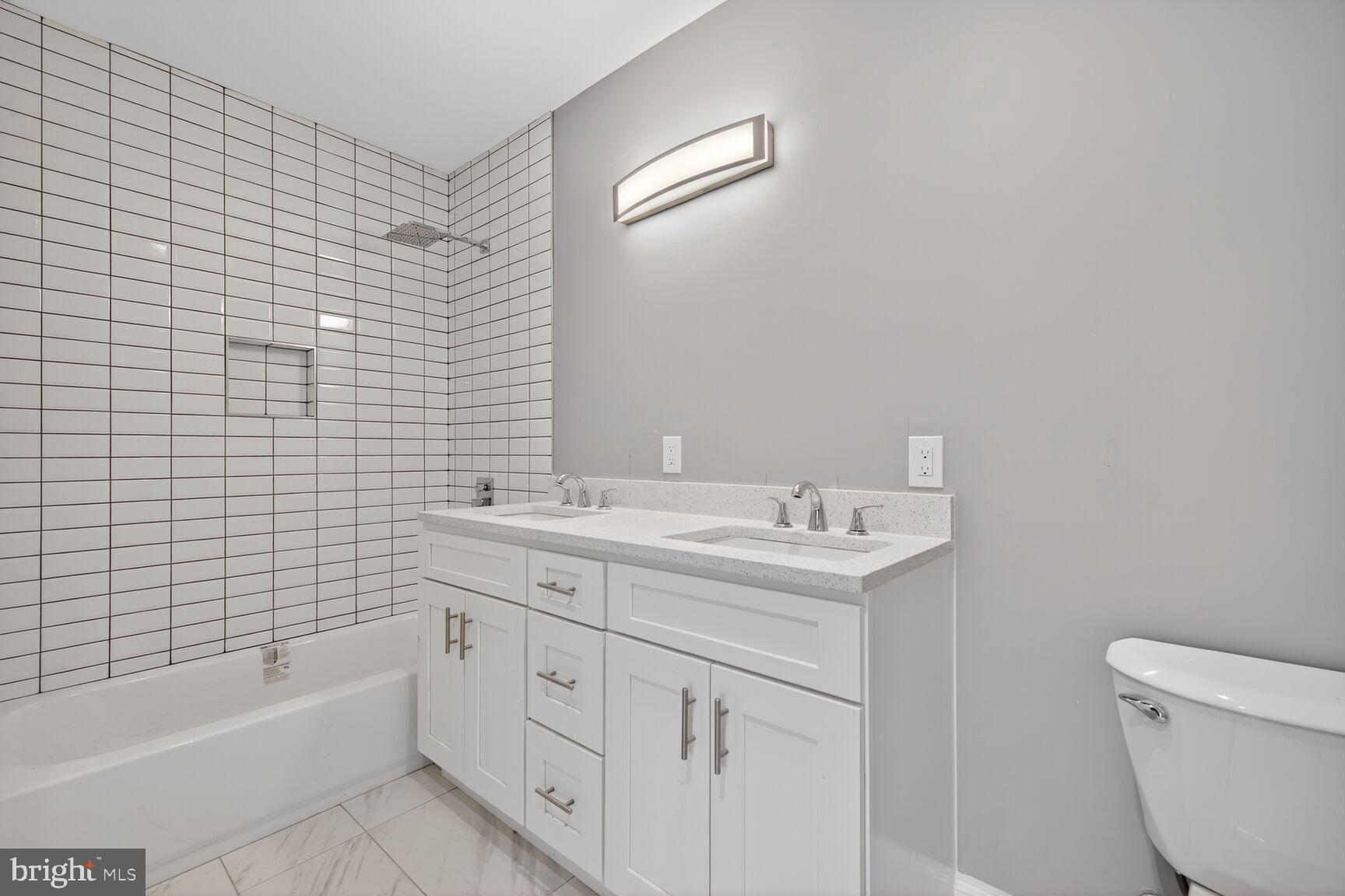 401 Linden Avenue Frederick, MD 21703 - Photo 22 of 29 a bathroom with a granite countertop toilet a sink a mirror a bathtub and shower