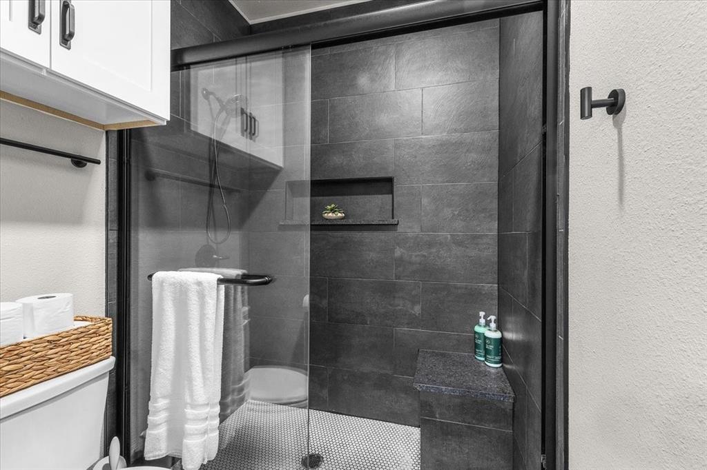 6080 Cates Rnch Drive Godley, TX 76044 - Photo 31 of 40 Glass enclosed shower featuring dark gray tile, built-in recessed shelf, built-in bench, and a rainfall shower head