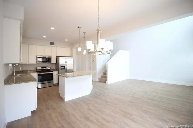 a large kitchen with kitchen island a stove a sink a center island and a wooden floor