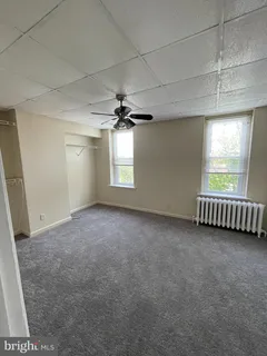 an empty room with windows and chandelier fan
