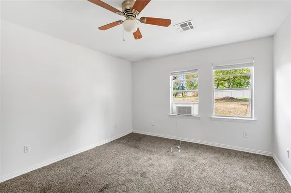 an empty room with windows and fan