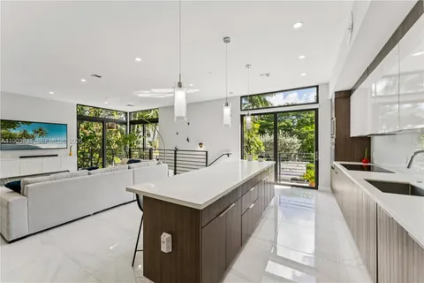 a large kitchen with stainless steel appliances a large counter top a stove a sink a refrigerator and a cabinets