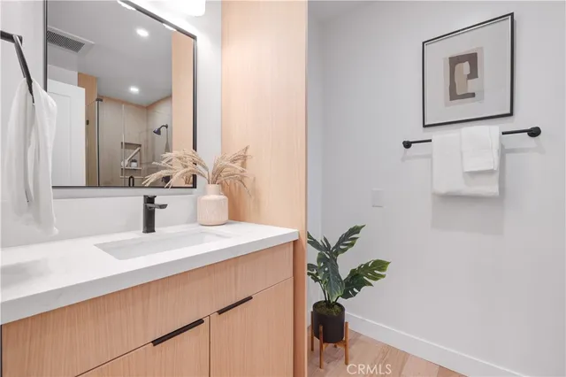 a bathroom with a sink a mirror and a potted plant