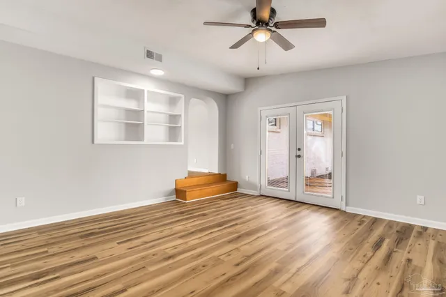 an empty room with wooden floor closet and windows