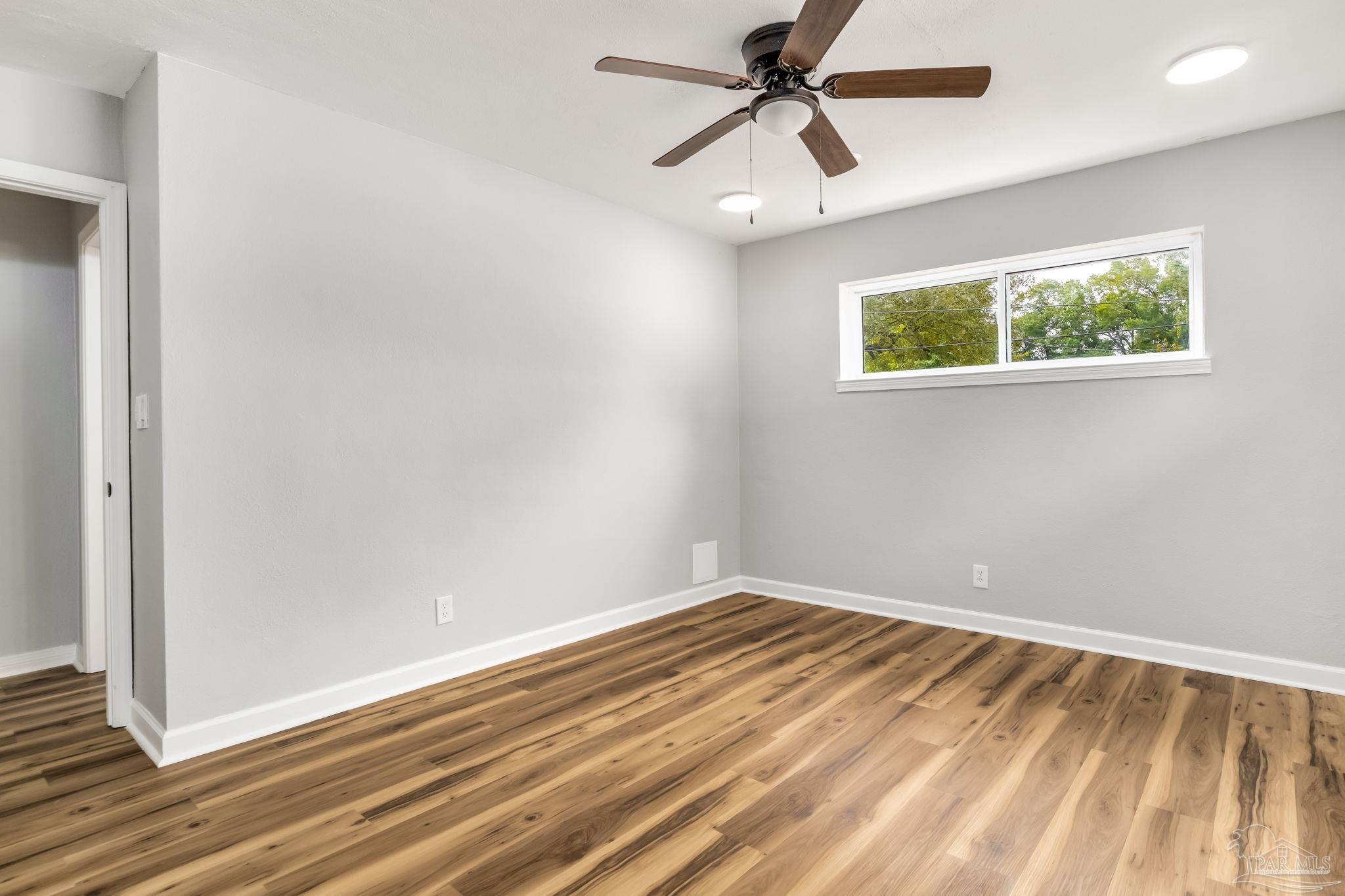 6357 Shady Lane Milton, FL 32570 - Photo 37 of 57 an empty room with wooden floor ceiling fan and windows