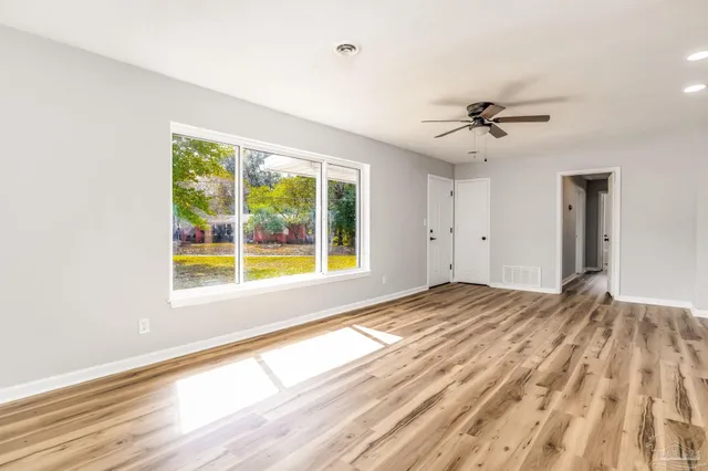 a view of empty room with wooden floor and fan